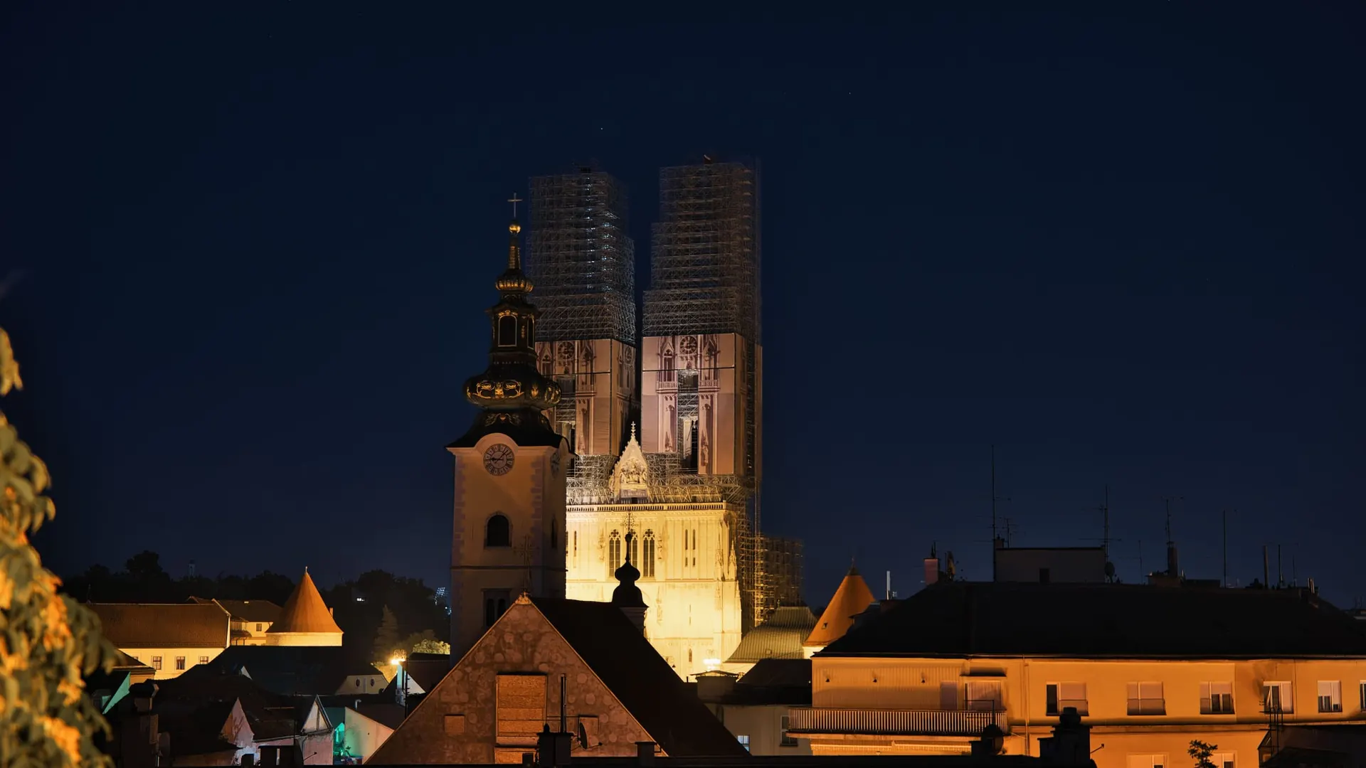Zagrebačka katedrala osvijetljena noću, tornjevi pod skelama, iznad krovova staroga grada.